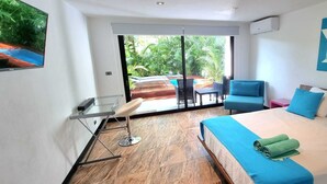 Una habitación de hotel con cama, escritorio y vista a un patio con mobiliario exterior.