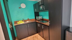 Una cocina compacta con armarios oscuros, un lavamanos y un microondas.