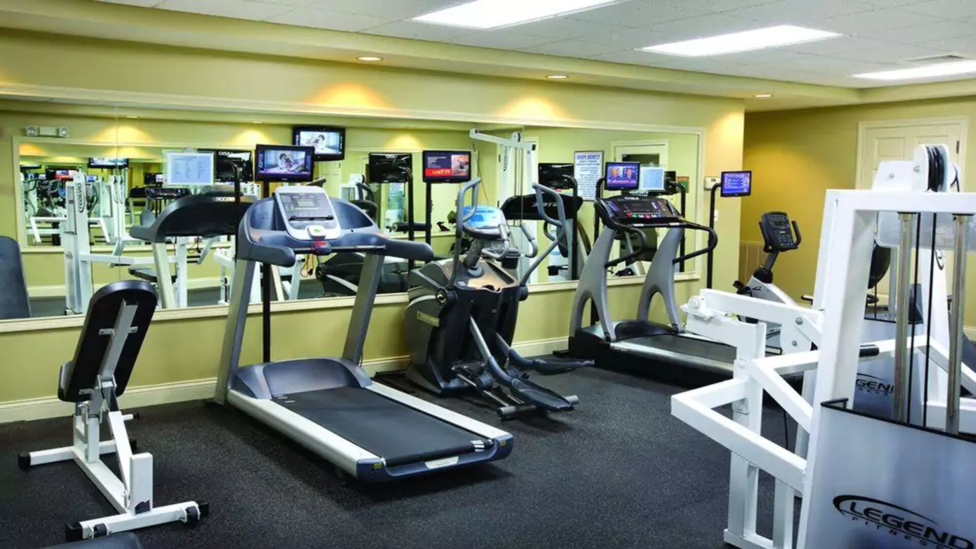 Ein Fitnessstudio mit Laufbändern, Kraftgeräten und Spiegeln.