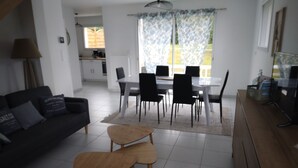 En moderne stue med sofa, sofabord og spiseområde med stole og bord.