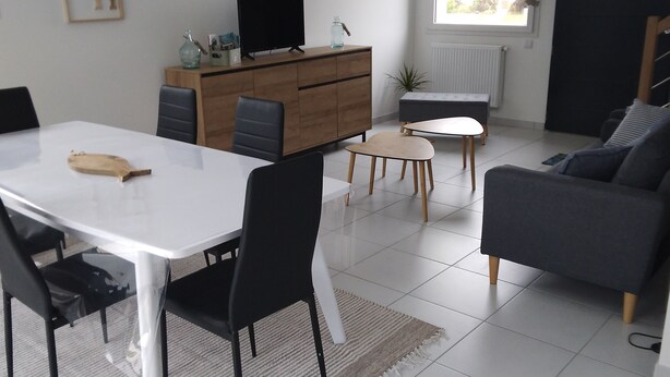 En moderne stue med spisebord, sofa og fjernsyn på et træskab.