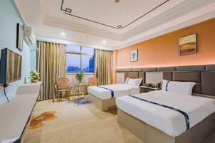 Quarto de hotel com duas camas, uma escrivaninha, uma cadeira e uma janela com cortinas.