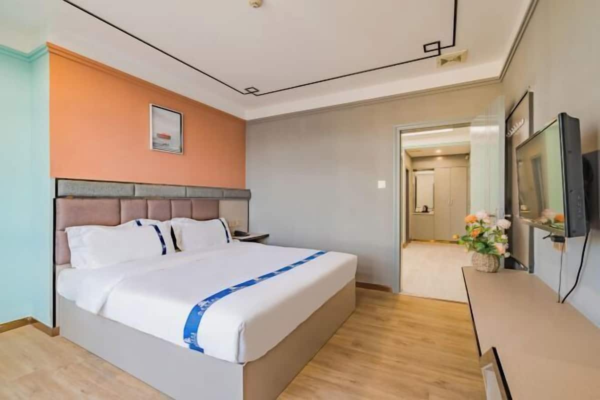 A hotel room with a bed, a nightstand, a TV, and a flower vase.