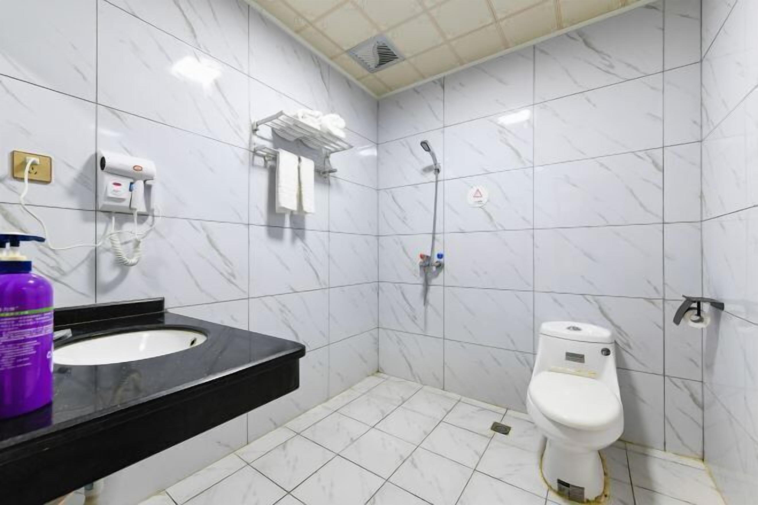 A bathroom with a black sink, white toilet, and a shower area.