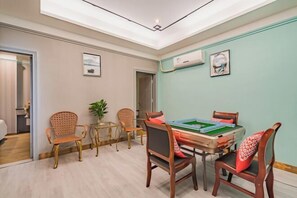 A room with a green pool table, wooden chairs, a potted plant, and a ceiling light. - Zhuxin Business Hotel (Huidong)