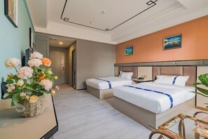A hotel room with two beds, a large vase of flowers, and a painting on the wall. - Zhuxin Business Hotel (Huidong)
