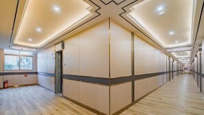 A corridor with wooden flooring, beige walls, and a ceiling with recessed lighting. - Zhuxin Business Hotel (Huidong)
