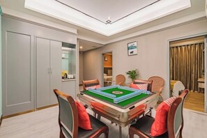 Een kamer met een pooltafel, stoelen, een kast en een plafondlamp.