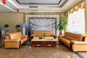 Un hall d’entrée avec des canapés en cuir, une table basse en marbre et une grande fresque murale abstraite.