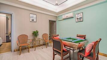 A room with a green felt table and chairs, a ceiling light, and a window with a view.
