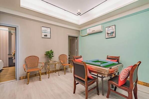 A room with a green felt table and chairs, a ceiling light, and a window with a view. - Zhuxin Business Hotel (Huidong)