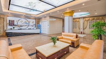 Un hall de hotel con mostrador de recepción, zona de estar y una gran pantalla digital.