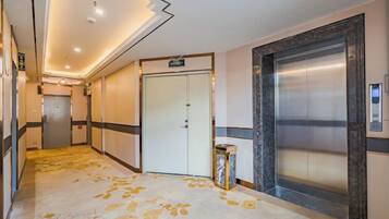 A hotel corridor with a carpeted floor, a closed door, and an elevator.