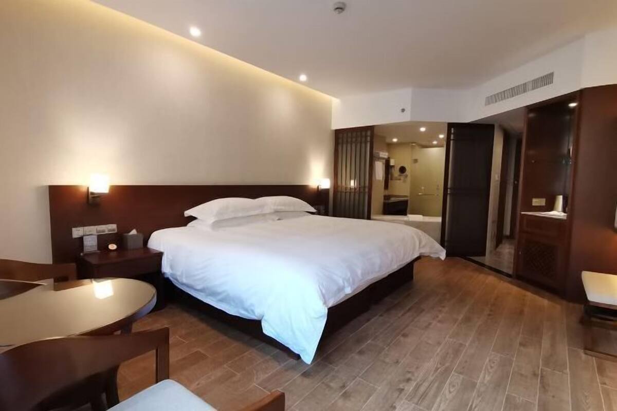 A hotel room with a bed, bedside tables, a desk, and a chair.