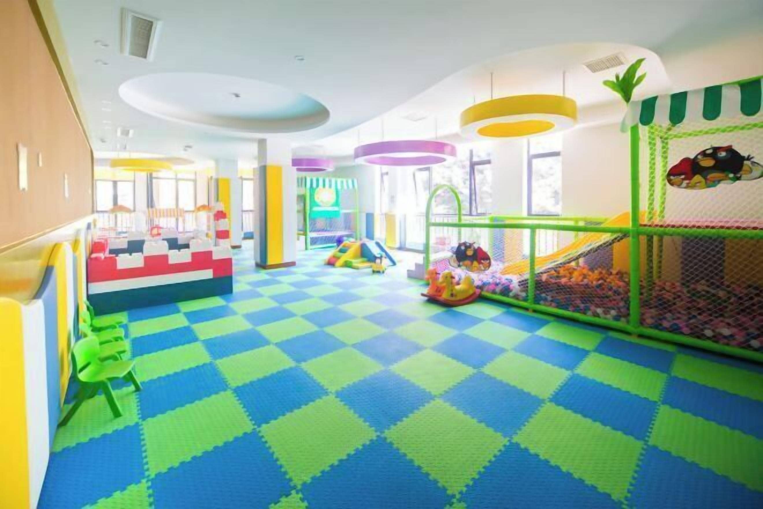 A children's play area with a checkered floor, play structures, and a ball pit.