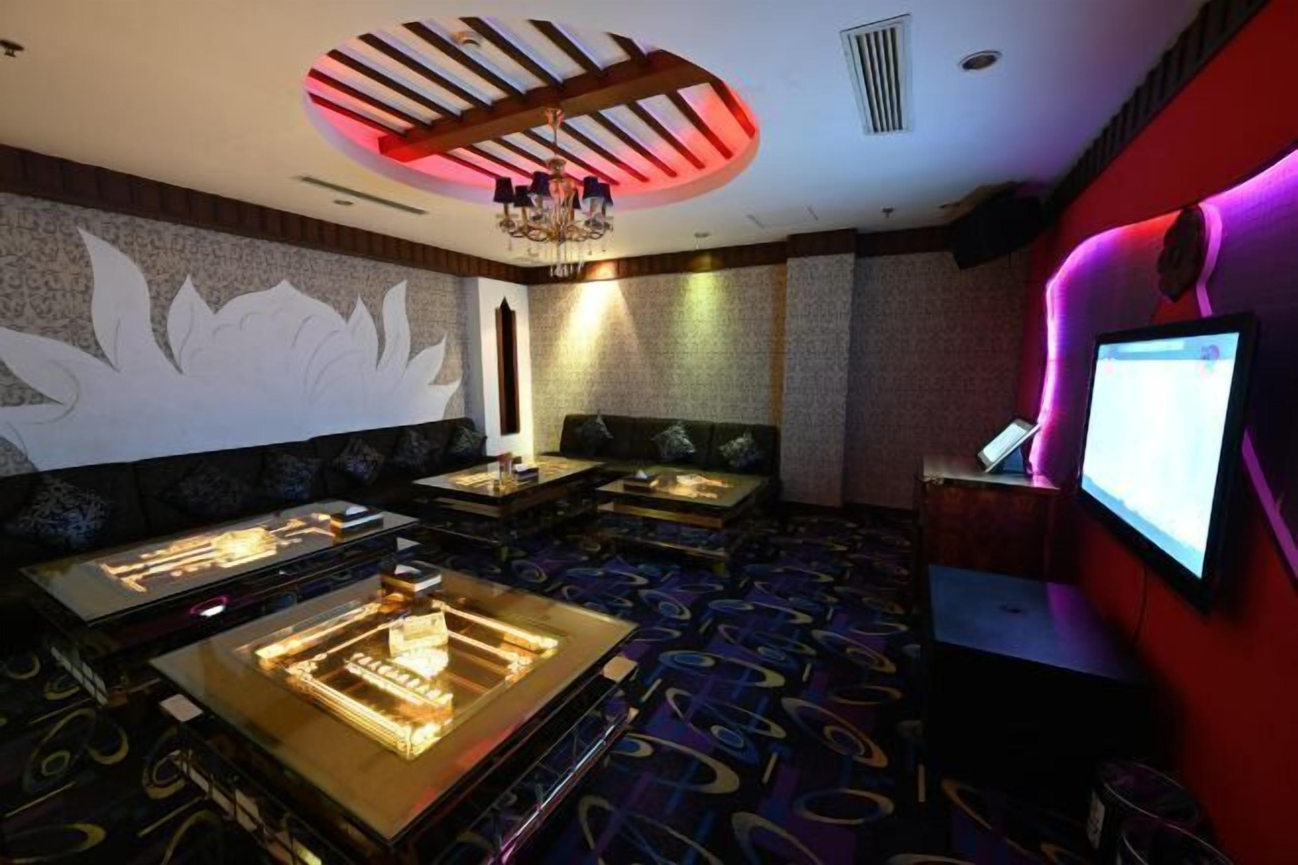 A room with a massage table, a massage chair, a TV, and a patterned carpet.