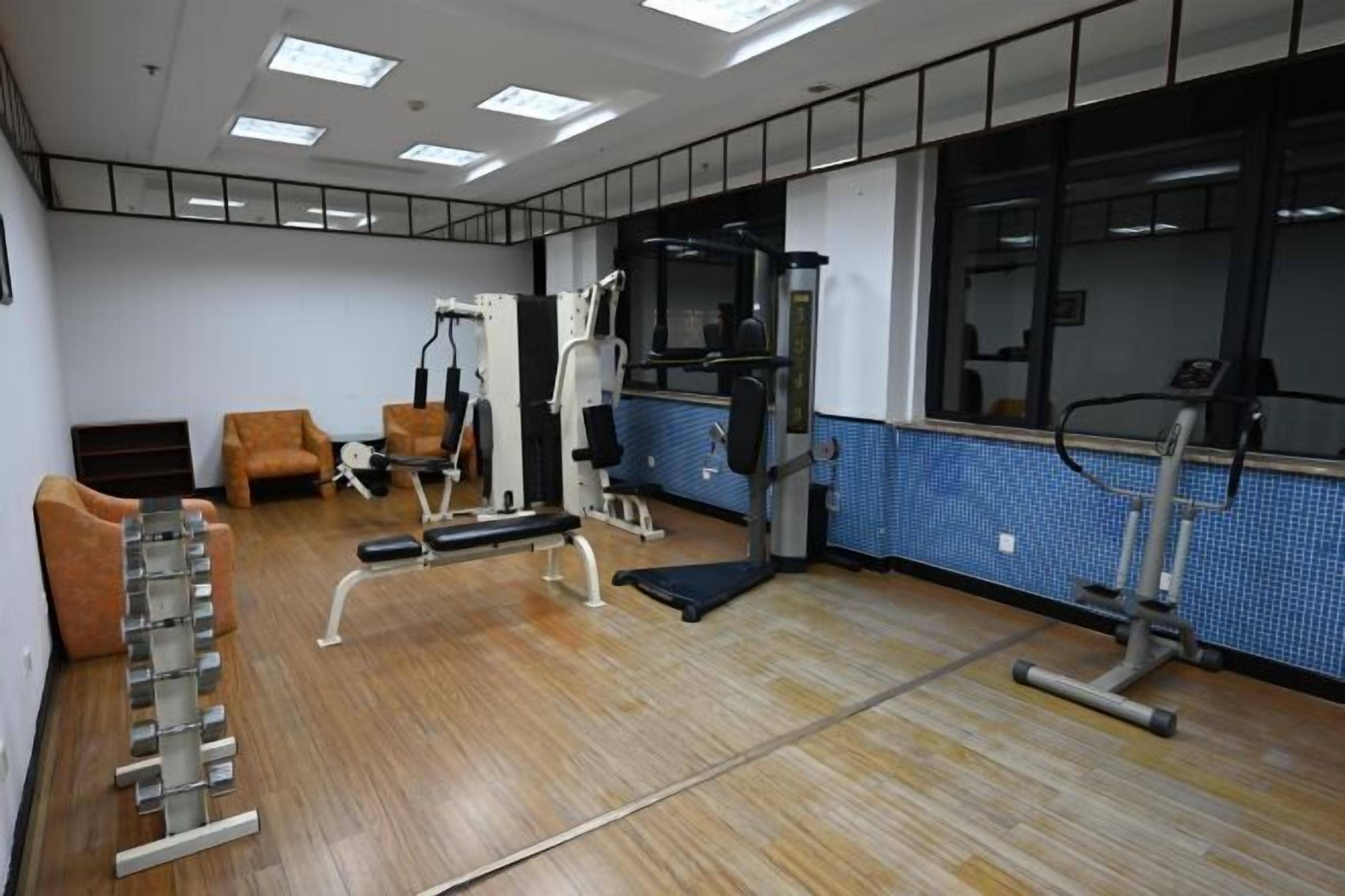 Une salle de sport équipée de matériel d’exercice, d’un miroir et d’un mur recouvert de carreaux bleus.
