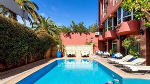 Una piscina con sillones de descanso y una pared de piedra.