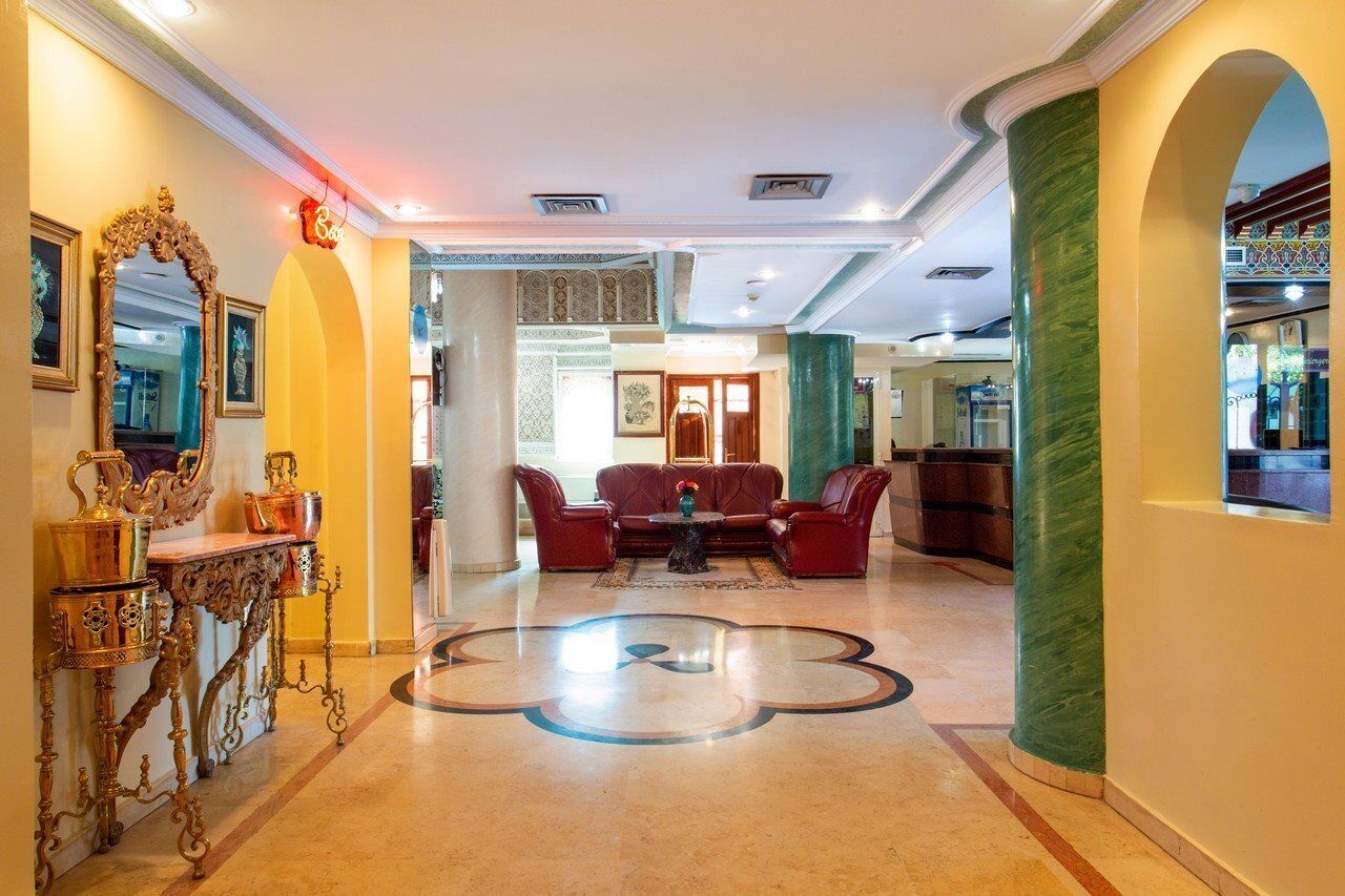 A lobby with a central seating area, a decorative mirror, and a patterned floor.