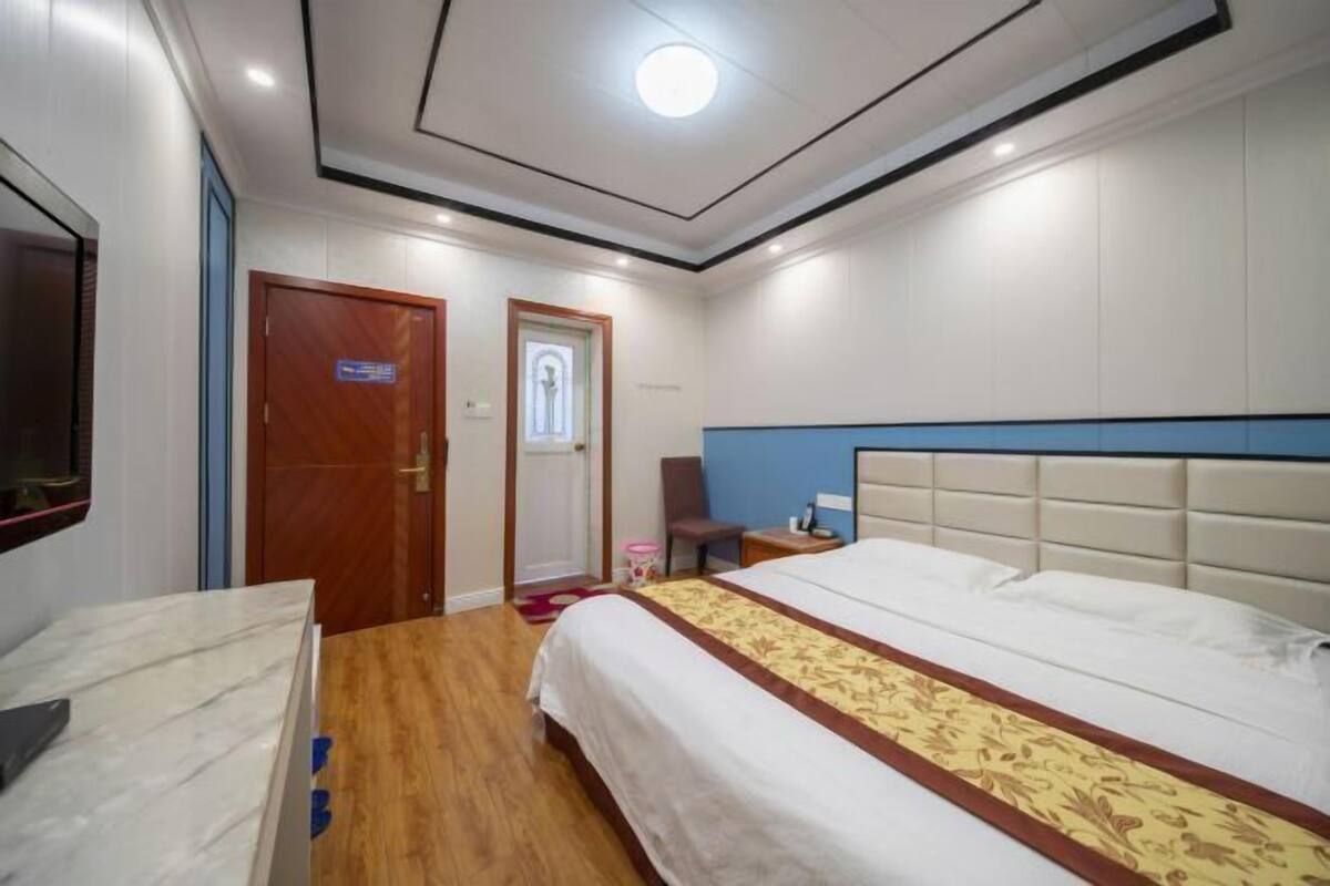 A hotel room with a bed, a desk, a chair, a television, and a door.