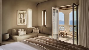 A bedroom with a bed, a sofa, a balcony with a view of the sea, and a framed artwork on the wall. - Omeon Mykonos (Mykonos)