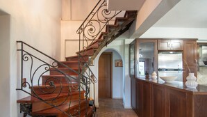 Eine Holztreppe mit aufwendiger Metallreling führt zu einem Küchenbereich mit Holzausbau und Arbeitsplatte.