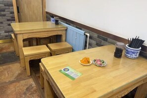 Una mesa de madera con un mantel individual, un plato de comida y un recipiente con cubiertos.
