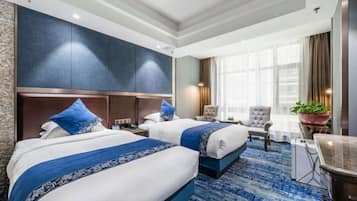A hotel room with two beds, a large window with curtains, a desk, and a chair.