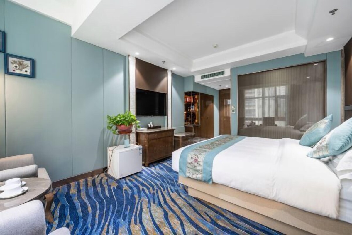Une chambre d’hôtel comprenant un lit, un bureau, une chaise, une télévision et une plante.