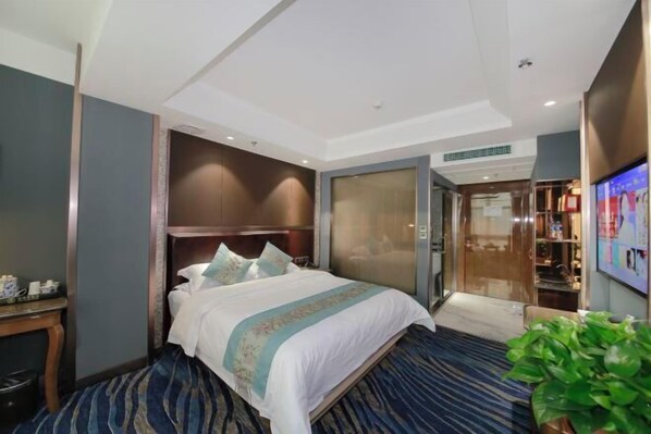 A hotel room with a large bed, a desk, a TV, and a wardrobe. - Ann Keats Hotel (Lanzhou)