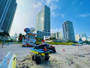 A beach with ATVs and a lifeguard tower. -  Lyfe Resort & Residences (Hollywood)