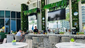 A modern bar area with a counter, seating, and a large TV screen. -  Lyfe Resort & Residences (Hollywood)