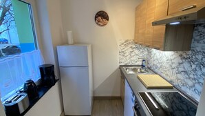 Una cocina compacta con refrigerador, estufa, lavamanos y armarios de madera.