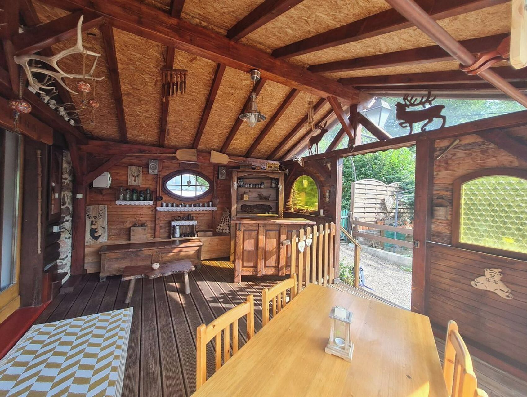Una cabaña rústica de madera con comedor, cocina y un amplio ventanal con vistas a un jardín.