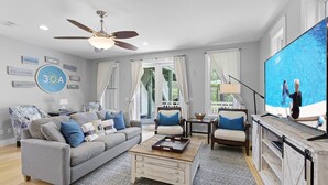 A living room with a grey sofa, blue cushions, a wooden coffee table, and a ceiling fan. - Hemingway at 30A - Seacrest, 12,000 Sq Ft Community Pool, Beach Tram, Bikes! (Seacrest Beach)