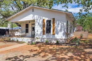 A single-story house with a porch, a covered entryway, and a small garden area.