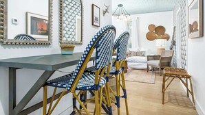 A dining area with a table and chairs, a mirror, and a wall with decorative items.