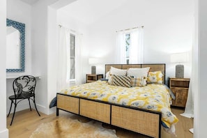 A bedroom with a bed, two bedside tables, a chair, and a mirror.