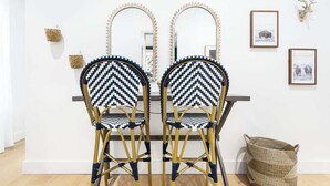 Two chairs with a geometric pattern, a woven basket, and a framed picture on a white wall.