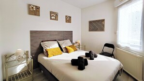 Een keurig ingerichte hotelkamer met een groot bed, een nachtkastje met lamp, een stoel en kunst aan de muur.