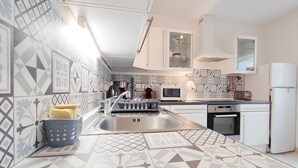 Een moderne keuken met geometrische tegelpatronen, roestvrijstalen apparatuur en witte kasten.