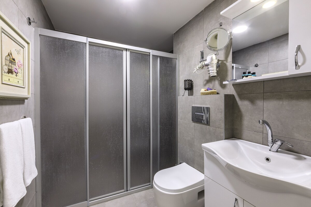 Een moderne badkamer met douche, toilet, wastafel en een spiegel.