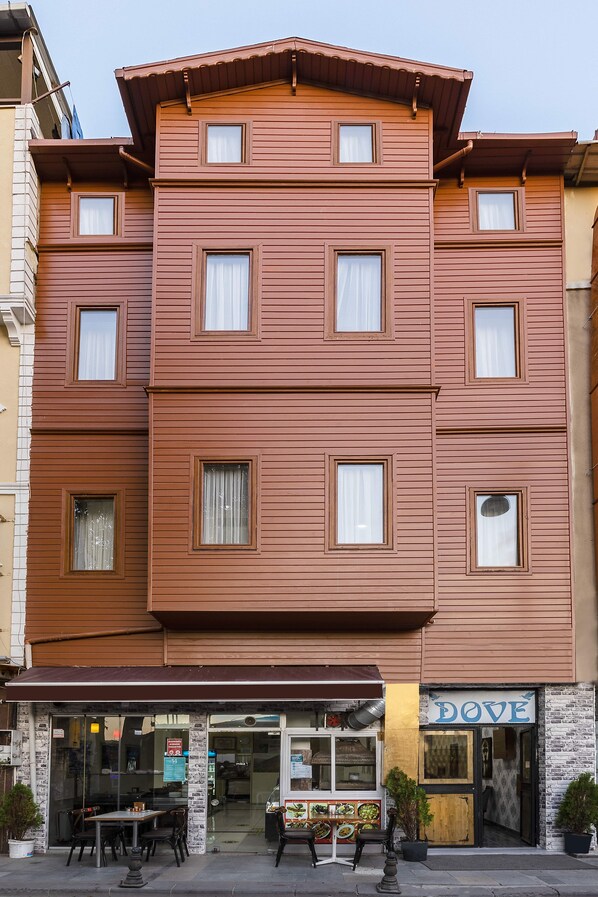 A multi-story hotel with a flat facade, multiple windows, and a ground-level restaurant with outdoor seating. - Astro Vefa (Istanbul)