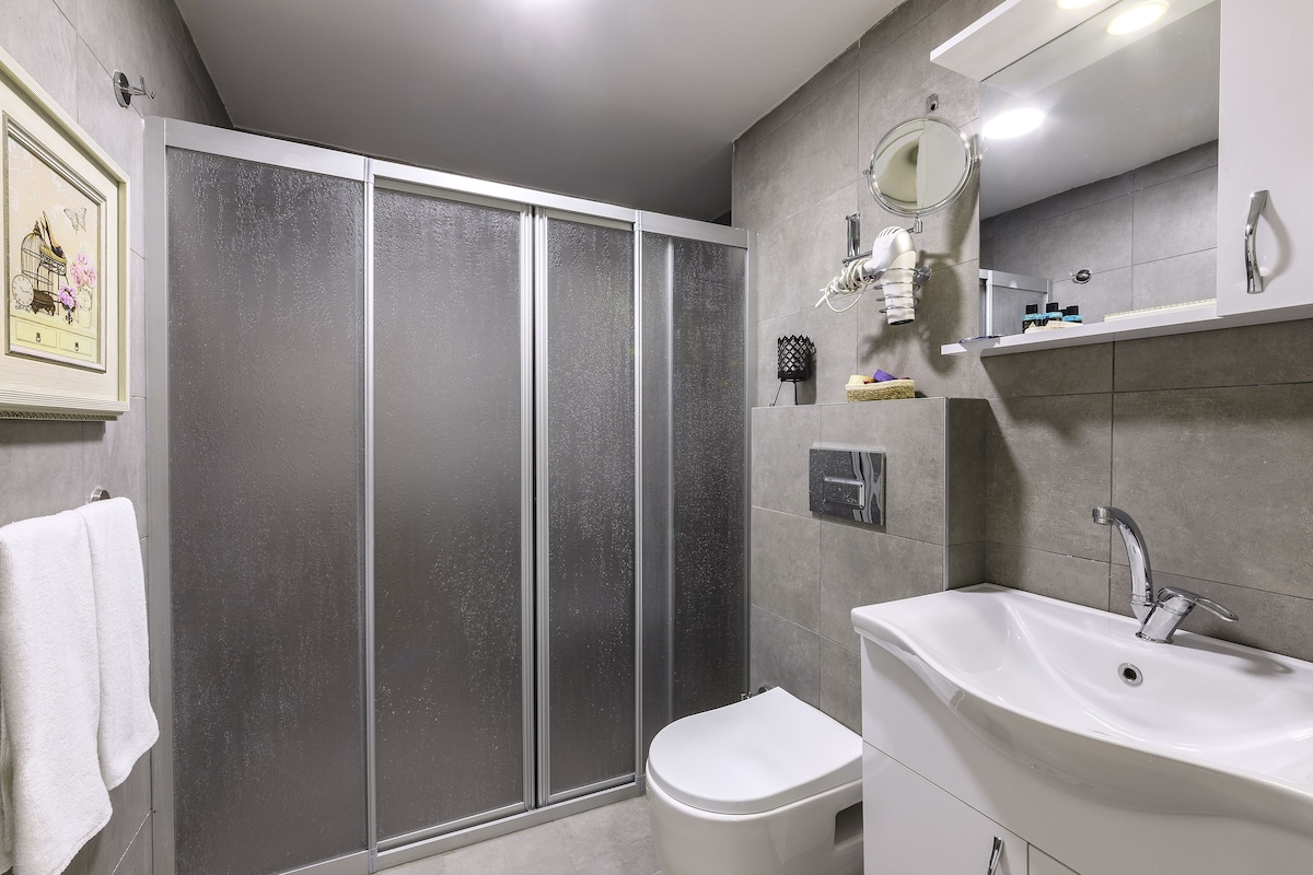 Ein modernes Badezimmer mit Dusche, Toilette, Waschbecken und Spiegel.