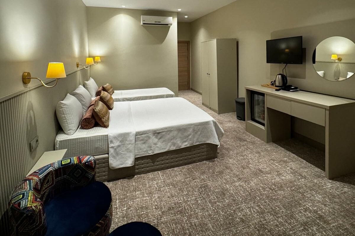 Ein Hotelzimmer mit zwei Betten, einem Schreibtisch, einem Fernseher und einer kleinen Sitzecke.