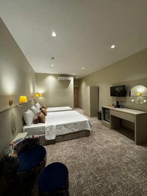 Une chambre d’hôtel avec deux lits, un bureau, une télévision et un petit coin salon.