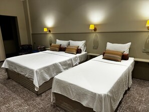 A hotel room with two beds, each with white linens and patterned pillows, a small bedside table, and a wall-mounted lamp. - Astro Vefa (Istanbul)