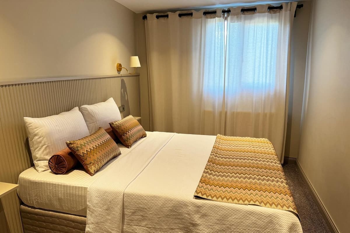 A neatly made bed with a patterned bedspread, two pillows, and a decorative pillow.