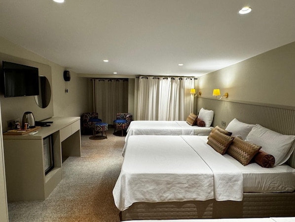 Une chambre d’hôtel avec deux lits, un bureau équipé d’une télévision, d’un téléphone et d’une chaise.