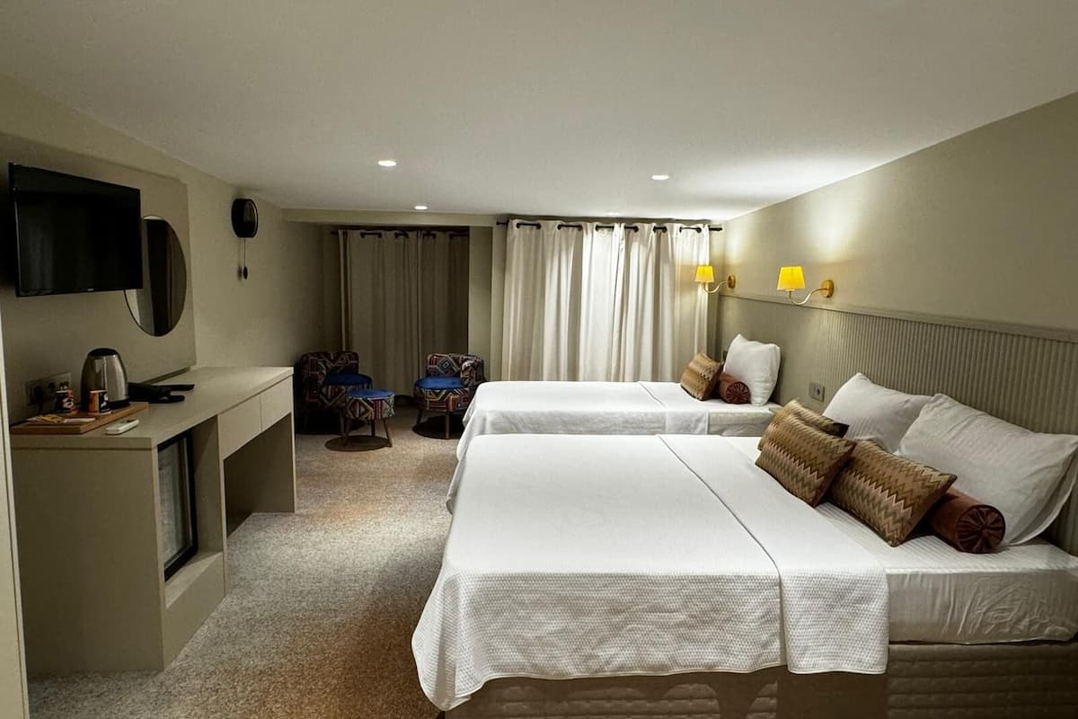 A hotel room with two beds, a desk with a TV, a telephone, and a chair.